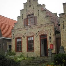 Pand met omlijste deur in gepleisterde trapgevel