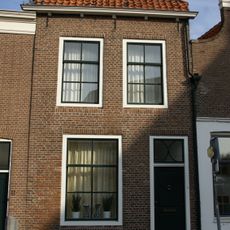 Woonhuis met gevel onder rechte lijst met consoles. Late Empire-schuif- en draairamen. Parterre en verdieping. Schilddak