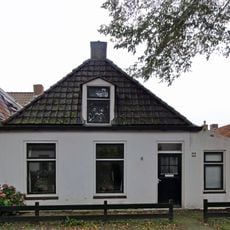 Pand met zesruitsvensters en houten goot op blokjes onder aan de voorzijde afgewolfd zadeldak