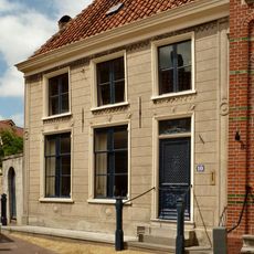 Gepleisterd pand bestaande uit een gedeelte met verdieping en schilddak