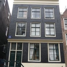 Huis met gevel onder rechte lijst waarboven een stenen punttopje uitsteekt