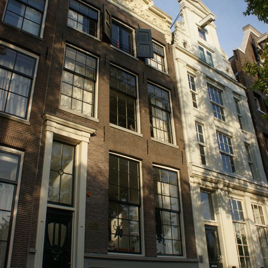 Pand met gevel onder rijk gebeeldhouwde stenen, in het midden verhoogde lijst met siervaas