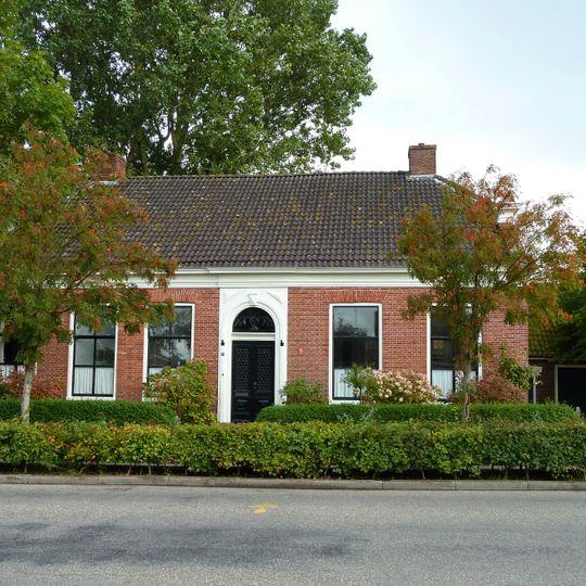 Pand met halfrond gesloten ingangsomlijsting onder dwars zadeldak met wolfseinden