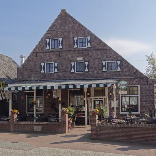 Huis/Herberg met hoge puntgevel, waarin onder de van vlechtingen voorziene top een zaagtandfries