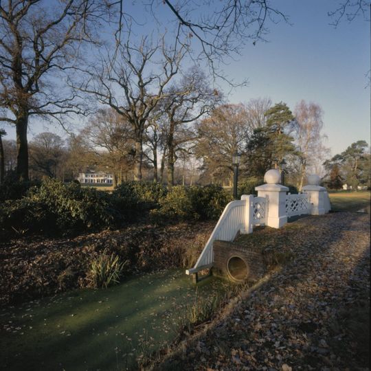 Zonnebeek: houten hek tussen twee vierkante pijlers onder deksteen met sierbol