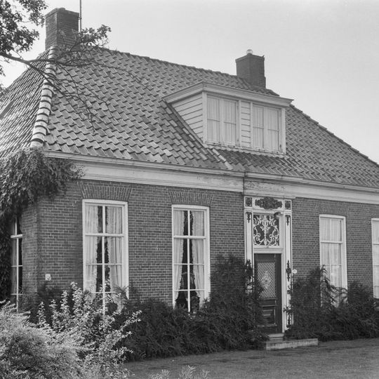 Breed woonhuis met omlijste ingang onder schilddak met hoekschoorstenen