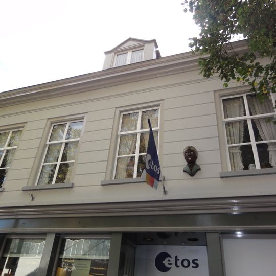 Huis met gebosseerd gepleisterde lijstgevel, moderne etalage