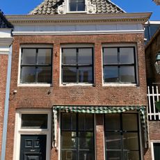 Pand met rechte kroonlijst onder schilddak met originele frontschoorsteen en dakkapel met snijwerk