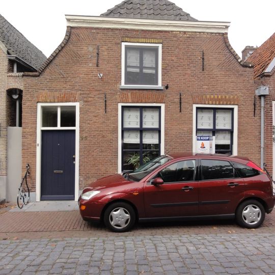 Huis onder schilddak en met lijstgevel waarvan de bovenhoeken ingezwenkt zijn