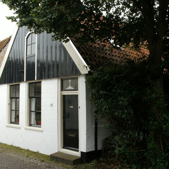 Diep pand waarvan een gevel aan de straat met houten voorschot waarin luik. Achterbouw en schuur