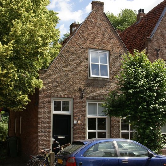 Huis onder zadeldak en met aan voor- en achterzijde een topgevel, naast oude stadhuis