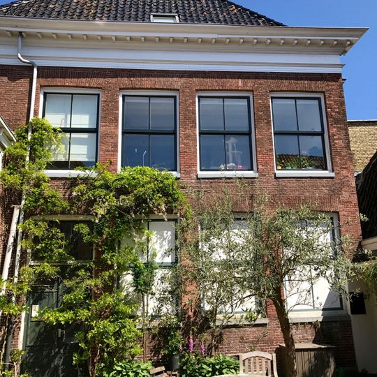 Inpandig gebouw met verdieping onder schilddak en forse kroonlijst met blokversiering