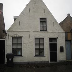 Pandje met voorgevel met beitelingen en uit het midden geplaatst zolderraam onder zadeldak tussen puntgevels