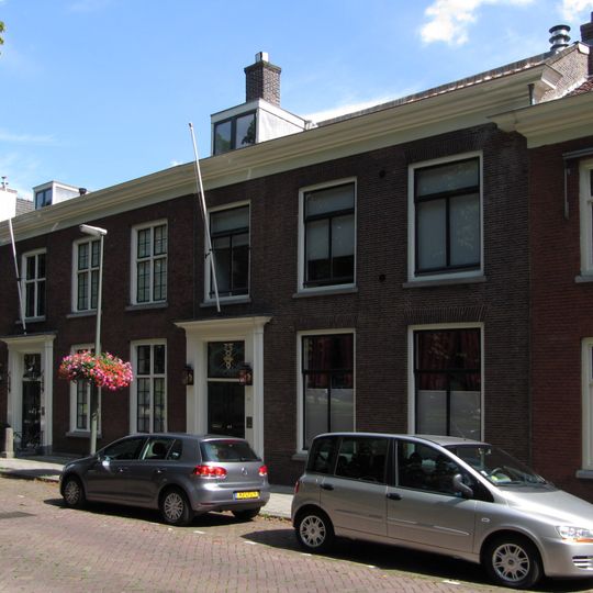 Herenhuis met eenvoudige lijstgevel. Deuromlijsting met hoofdgestel, oorspronkelijke dubbele deur en gesneden bovenlicht. Hardstenen stoeppalen met zwarte versieringen