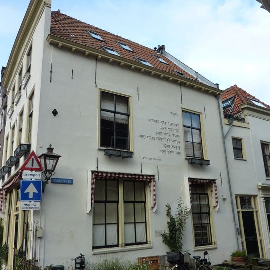 Brede gepleisterde gevel met rechte kroonlijst, ouder huis aanwezig