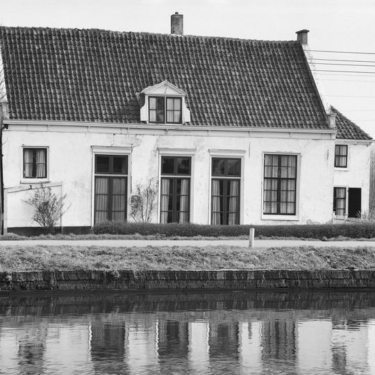 Lage witgepleisterde hofstede met uitbouw, zadeldak in topgevels eindigend