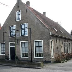 Bakstenen woonhuis met schoolruimte ondergebracht in het achterhui