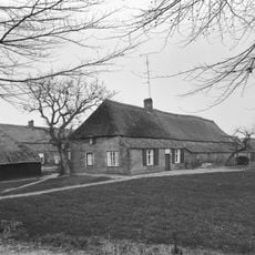 Boerderij van het Kempische langgeveltype, met rieten wolfdak met voet van pannen, met vrijstaande deels bakstenen, deels houten schuur onder rieten wolfdak.