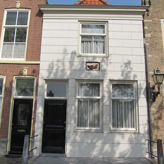 Huis met gepleisterde gevel onder lijst met gevelsteen waarop schip en jaartal