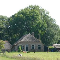 Boerderij onder rieten wolfdak en met vensters, waarin 30-ruitsroedenverdeling