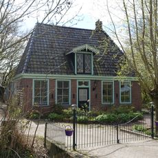 Aardig rechthoekig pandje onder hoog schilddak met hoekschoorstenen en dakkapel