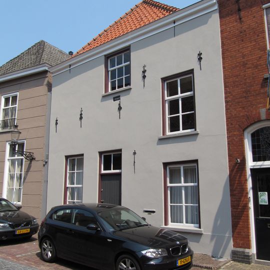 Huis met witgepleisterde lijstgevel en hoog schilddak