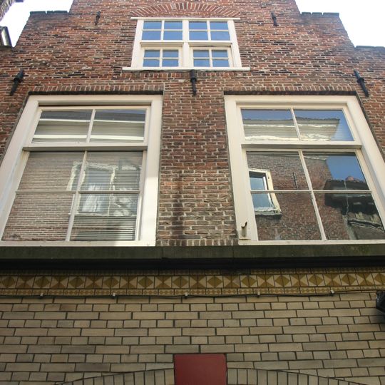 Pand met trapgevel met kruiskozijn. Onderpui verbouwd