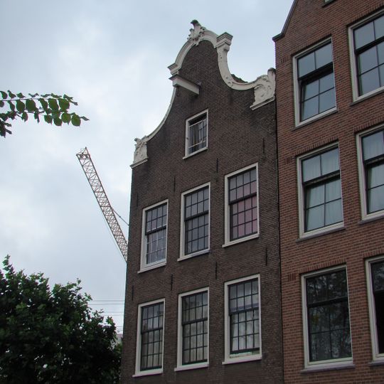 Huis, vanwege de zandstenen onderdelen van de klokvormige top en de gesneden puilijst