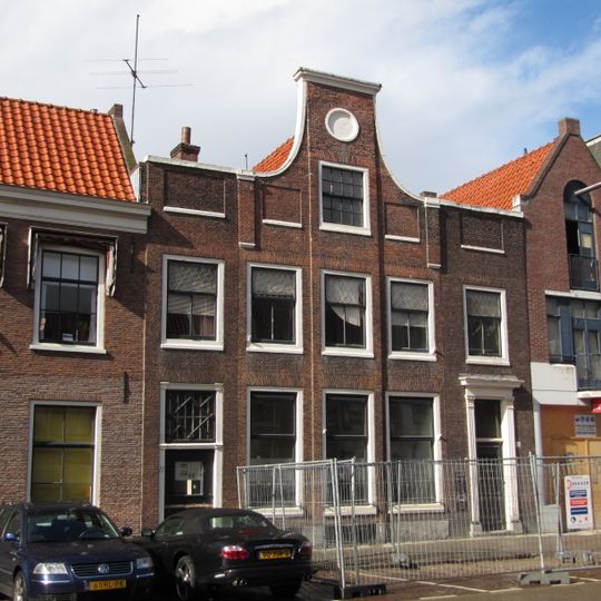 Pand met klokgevel, 2e helft 17e eeuw, aan weerszijden uitgebouwde vleugels met rechte kroonlijsten, waarin zich toegangen bevinden