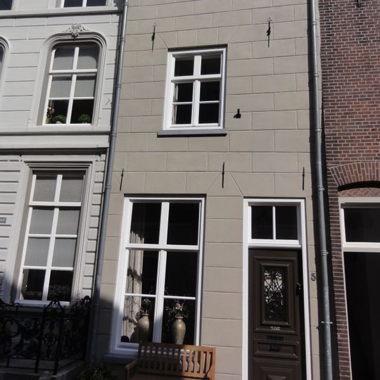 Eenvoudig huis met gebosseerd geelgepleisterde lijstgevel, schilddak, ankers