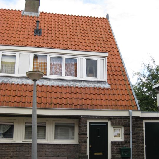 Blok met 8 keukenwoningen, zo genoemd vanwege destijds nieuwe plaatsing van keuken aan de voorzijde, aan de zijkant een houten topgevel, bouwstijl Amsterdamse School.