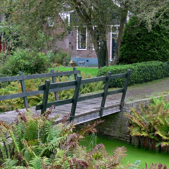 Brug die de verbinding vormt tussen het perceel waarop de vermaning en kosterswoning zijn gelegen en de evenwijdig aan de sloot lopende weg.
