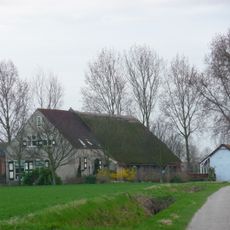 Woonhuis in gele baksteen met rode bakstenen lagen en hoekbanden, benevens korfbogen in topgevel van rode baksteen gepleisterde langsgevel met pannen zadeldak.
