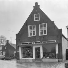 Pand onder pannen zadeldak tussen hoge puntgevels met vlechtingen.