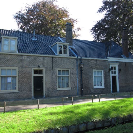 Boerderij, waarvan het woongedeelte een met pannen gedekt draagt. Houten kroonlijst en vensters met achtruitsschuiframen uit de eerste helft van de 19e eeuw.