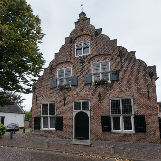 Woonhuis met gezwenkte trapgevel; boven de vensters korfbogen en op de verdiepingen uitgekraagde bogen. Toppilasters met trapje