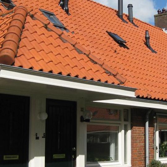 Blok met 9 woningen, gecombineerde toegangen van twee woningen onder een ingestoken schilddak, zijkant met houten topgevel, onderdeel van complex bejaardenwoningen in Tuindorp Nieuwendam
