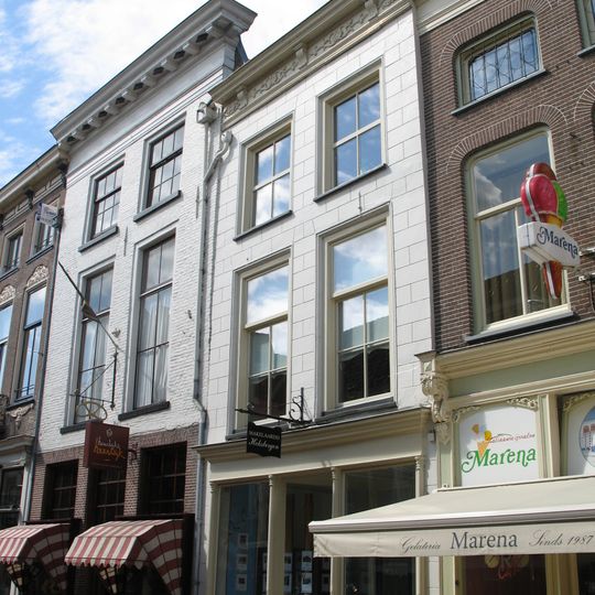 Huis met in blokken gepleisterde lijstgevel met consoles en met jongere winkelpui