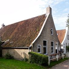 Pand met zesruitsvensters en houten goot op blokjes onder aan de voorzijde afgewolfd zadeldak