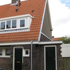 Blok met 8 keukenwoningen, zo genoemd vanwege destijds nieuwe plaatsing van keuken aan de voorzijde, aan de zijkant een houten topgevel, bouwstijl Amsterdamse School.
