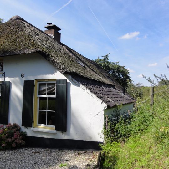 Gepleisterde, tegen de dijkvoet gebouwde boerderij
