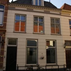 Huis met gepleisterde lijstgevel met in de verdieping schuiframen en dakvenster met balustrade