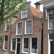 Pand onder zadeldak tegen klokgevel met aanzetkrullen en deklijst