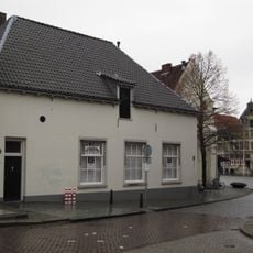 Laag pand met hoog zadeldak en gepleisterde lijstgevel