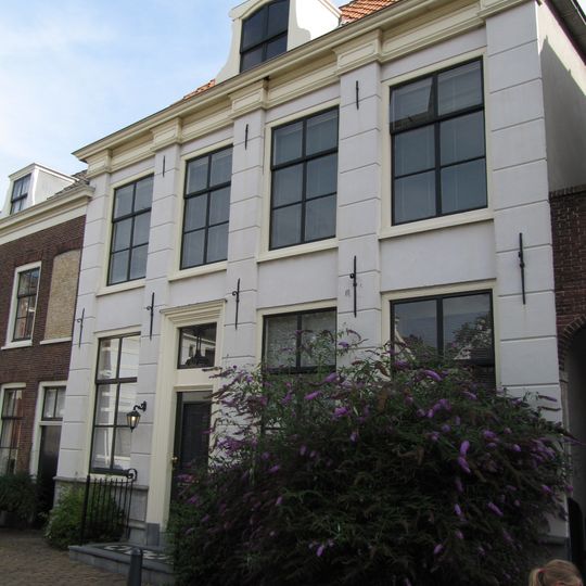 Pand met pilastergevel met rechte kroonlijst. Gepleisterd