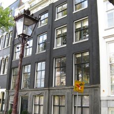 Huis, samengesteld uit een oud linkerdeel met gevel onder rechte lijst en attiek, met hoeklisenen en gebeeldhouwde onderpui en een in stijl daarbij aangepast nieuw rechter gedeelte