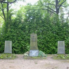 Denkmalanlage für die Gefallenen des Ortes im 1. und 2. Weltkrieg, drei Granitsteine mit Inschriften, Baumpflanzungen und Gehölze entlang der zentralen Wegeachse (Flurstück 671)