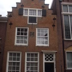 Huis met trapgevel met sierankers en wapensteen. Gerestaureerd