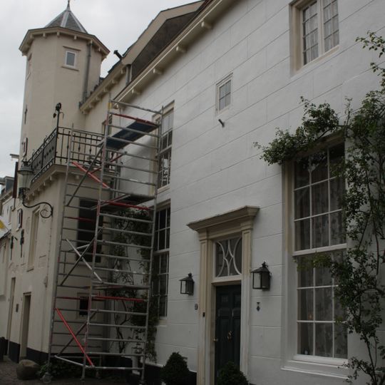 Huis met gepleisterde gevel met rechte kroonlijst. Omlijste voordeur
