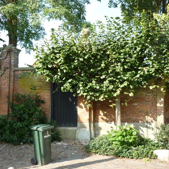 Twee gemetselde hekpijlers met natuurstenen dekplaten, waarop ballen.